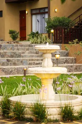 a white fountain in front of a house at Monteverde Country Lodge - Costa Rica in Monteverde Costa Rica
