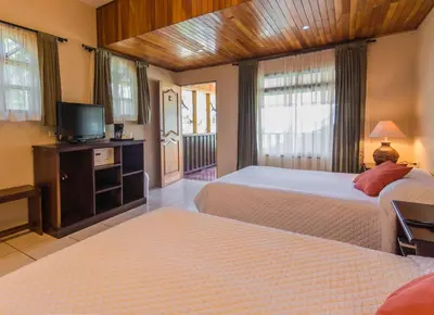 a hotel room with two beds and a television at Monteverde Country Lodge - Costa Rica in Monteverde Costa Rica