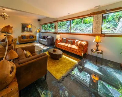 a living room with couches and tables and windows at Hotel & Spa Poco a Poco - Costa Rica in Monteverde Costa Rica