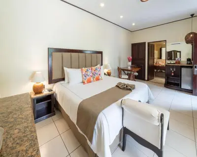 a bedroom with a large bed and a kitchen at Hotel & Spa Poco a Poco - Costa Rica in Monteverde Costa Rica