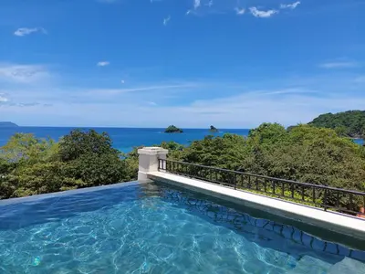 a swimming pool with the ocean in the background at Santarena Hotel at Las Catalinas in Playa Flamingo