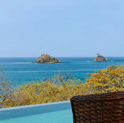 a wicker chair sitting next to a view of the ocean at Santarena Hotel at Las Catalinas in Playa Flamingo