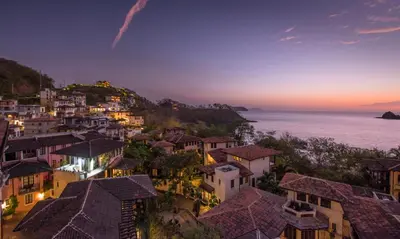 a view of a town at night with the ocean at Santarena Hotel at Las Catalinas in Playa Flamingo