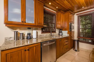 a kitchen with wooden cabinets and a stainless steel refrigerator at Jet Luxury at Langosta Beach Resort & Villas in Tamarindo