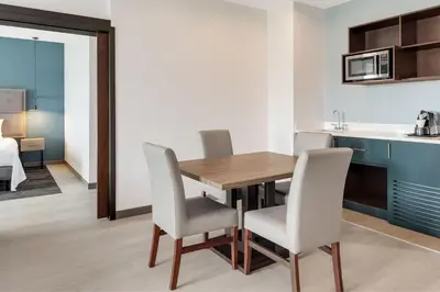 a kitchen and dining room with a wooden table and chairs at Courtyard by Marriott San Jose Airport Alajuela in Alajuela City