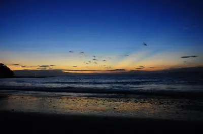 a sunset on a beach with the ocean at Hotel Punta Leona in Jacó