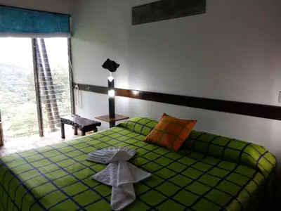 a bedroom with a green bed with towels on it at Celeste Mountain Lodge in Bijagua