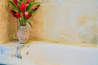 a bathroom sink with a vase with flowers in it at Makara Toucan Suite / 2nd Floor in Uvita