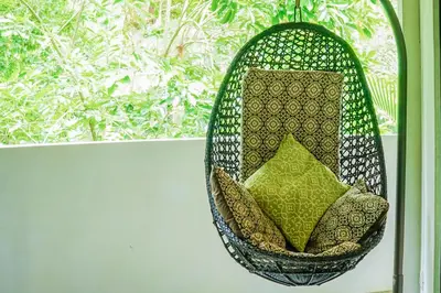 a wicker chair with pillows sitting in front of a window at Makara Toucan Suite / 2nd Floor in Uvita