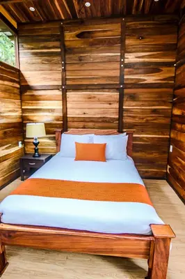 a bed in a room with wooden walls at Casa Higueron in Monteverde Costa Rica