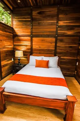 a bed in a room with wooden walls at Casa Higueron in Monteverde Costa Rica