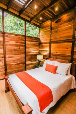 a bedroom with a bed in a room with wooden walls at Casa Higueron in Monteverde Costa Rica