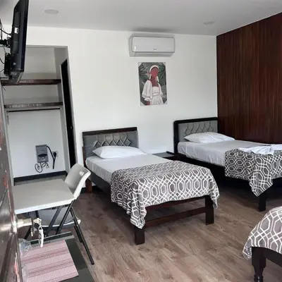 a room with two beds and a chair in it at Hotel Naralit in Tilarán