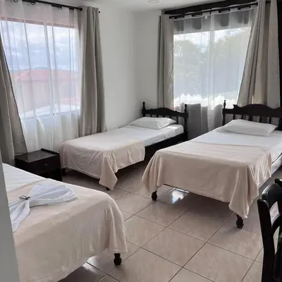 a room with three beds and a window at Hotel Naralit in Tilarán
