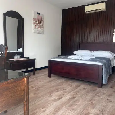 a bedroom with a bed and a vanity and a mirror at Hotel Naralit in Tilarán