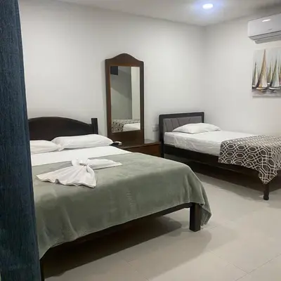 a hotel room with two beds and a mirror at Hotel Naralit in Tilarán