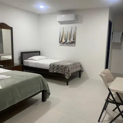 a bedroom with two beds and a mirror and a chair at Hotel Naralit in Tilarán