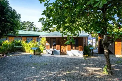 a house with a tree in front of it at Karandi Hostel in Uvita