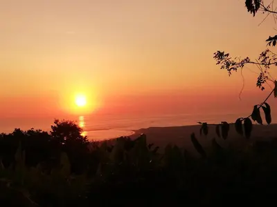a sunset over the ocean with the sun in the sky at Karandi Hostel in Uvita