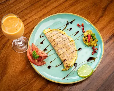 a plate with a piece of fish and a glass of orange juice at Lodge Las Estrellas de Samara - Ocean View in Sámara