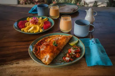a wooden table with two plates of food and drinks at Lodge Las Estrellas de Samara - Ocean View in Sámara