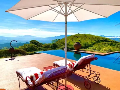a pool with two chairs and an umbrella at Magic Mountain Views Villa in Atenas