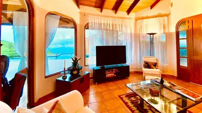 a living room with a tv and some windows at Magic Mountain Views Villa in Atenas