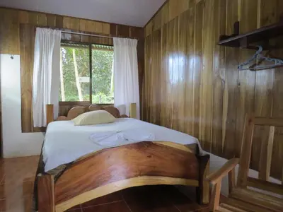 a bedroom with a bed with a wooden wall at Poponjoche Lodge Caño Negro in Caño Negro
