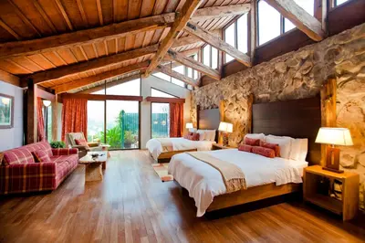 a large bedroom with two beds and a stone wall at Poas Volcano Lodge in Vara Blanca
