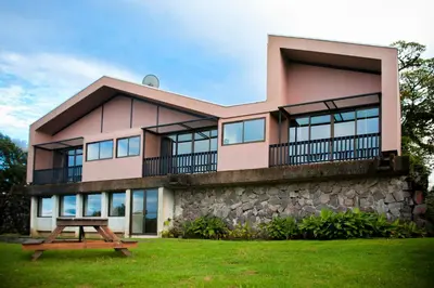 a pink house with a picnic table in front of it at Poas Volcano Lodge in Vara Blanca