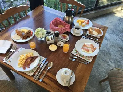 a wooden table topped with plates of breakfast food at Poas Volcano Lodge in Vara Blanca