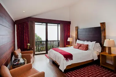 a bedroom with a large bed and a balcony at Poas Volcano Lodge in Vara Blanca