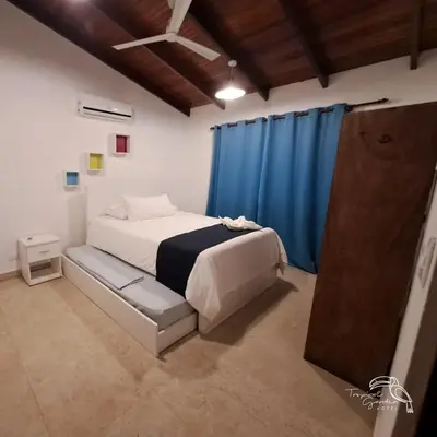 a bedroom with a bed and a blue curtain at Tropical Garden Hotel in Jacó