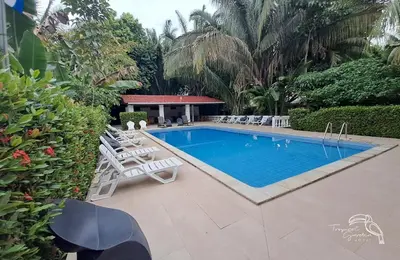 a swimming pool with lounge chairs next to a resort at Tropical Garden Hotel in Jacó