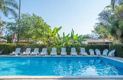 a swimming pool with chaise lounge chairs and a swimming pool at Tropical Garden Hotel in Jacó