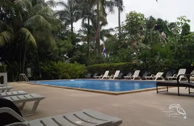 a swimming pool with chaise lounges and lounge chairs at Tropical Garden Hotel in Jacó