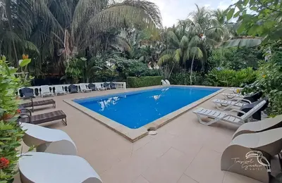 a swimming pool with chaise lounge chairs and a swimming pool at Tropical Garden Hotel in Jacó