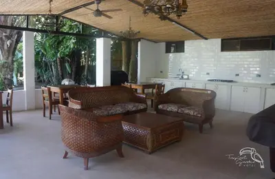 a living room with chairs and a table and a kitchen at Tropical Garden Hotel in Jacó