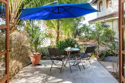 a patio with a table and chairs and a blue umbrella at El Castillo Luxury Boutique Hotel- in Ojochal