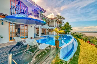 a house with a swimming pool and two chairs at El Castillo Luxury Boutique Hotel- in Ojochal
