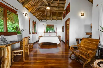 a bedroom with a bed and chairs in a room at Copa De Arbol Beach & Rainforest Resort in Drake
