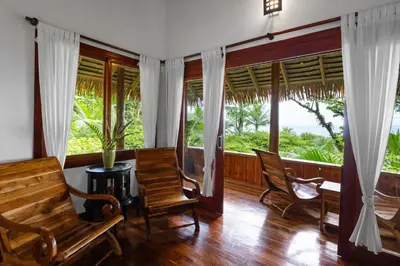 a room with chairs and windows with a view of the ocean at Copa De Arbol Beach & Rainforest Resort in Drake