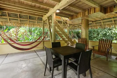 a dining room with a table and chairs and a hammock at Copa De Arbol Beach & Rainforest Resort in Drake