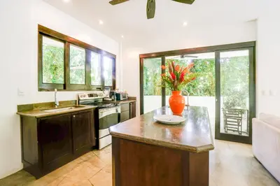 a kitchen with an island with a vase of flowers on it at Makara Suite Mariposa Ground Floor in Uvita