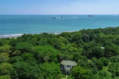 an aerial view of a house in the forest with the ocean at Makara Suite Mariposa Ground Floor in Uvita