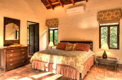 a bedroom with a bed and a dresser and windows at Hacienda Barrigona in Sámara