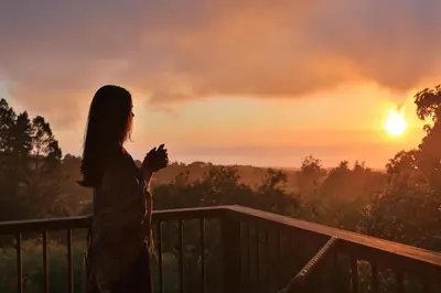 a woman standing on a balcony watching the sunset at Senda Monteverde Hotel Member of the Cayuga Collection in Monteverde Costa Rica