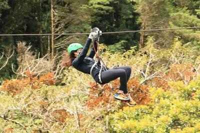 a woman is hanging on to a rope on a zip line at Senda Monteverde Hotel Member of the Cayuga Collection in Monteverde Costa Rica