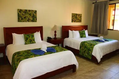 a hotel room with two beds with towels on them at La Foresta Nature Resort in Quepos