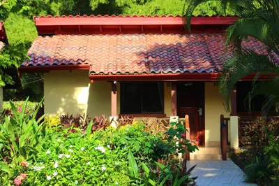 a house with a red roof and some plants at La Foresta Nature Resort in Quepos
